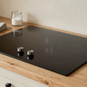 Plaque vitrocéramique noire impeccable dans une cuisine lumineuse, avec chiffon microfibre et bocal de bicarbonate