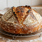 Pain de campagne rond à la croûte dorée et grignée, refroidissant sur une grille