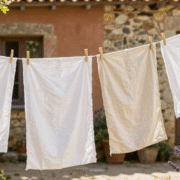 Draps blancs en coton et lin séchant au grand air sur un fil, dans un jardin de campagne