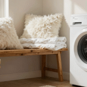Oreillers et couette blancs empilés près d'un lave-linge dans une buanderie lumineuse