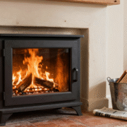 Vitre d'insert parfaitement transparente devant les flammes, seau de cendre et journal posés sur l'âtre