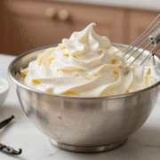 Chantilly ferme et brillante dans un bol en inox glacé, avec fouet, sucre glace et gousse de vanille