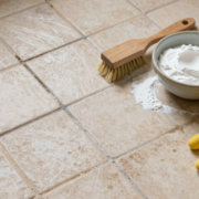 Joints de carrelage au sol à moitié blanchis, avec brosse et pâte de bicarbonate