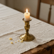Bougeoir en laiton et coulures de cire figées sur une nappe en lin blanc