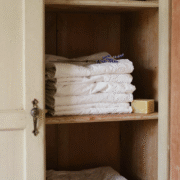 Armoire ancienne entrouverte avec du linge plié, de la lavande séchée et un cube de savon de Marseille