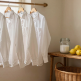 Chemises blanches suspendues près d'une fenêtre avec bicarbonate, citrons et savon de Marseille sur une étagère