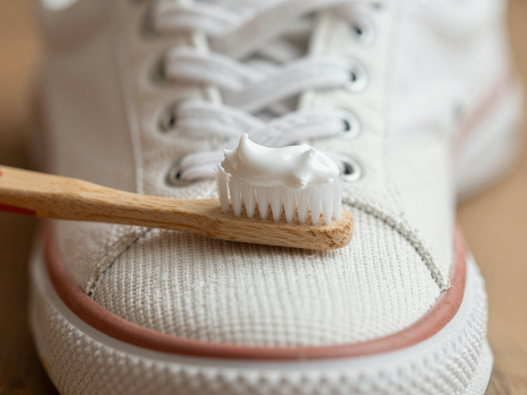Brosse à dents garnie de pâte de bicarbonate posée sur le bout d'une basket en toile blanche