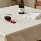 Verre de vin rouge renversé sur une nappe blanche, avec une bouteille d'eau gazeuse prête pour le détachage